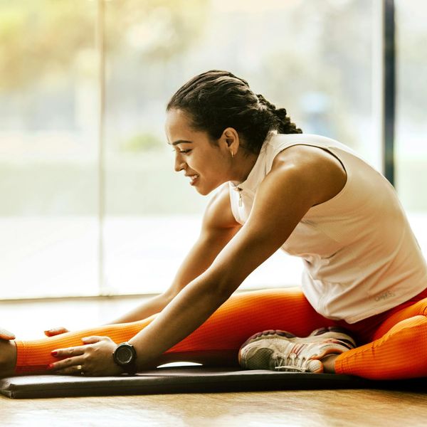 Smiling woman stretching in a bright room, conveying a sense of energy and well-being.